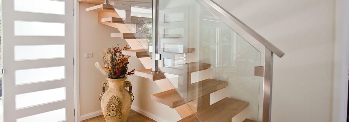 Modern wooden staircase with glass panels in a residential interior.