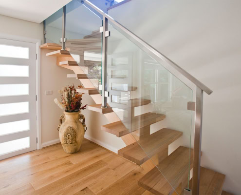 Modern wooden staircase with glass panels in a residential interior.
