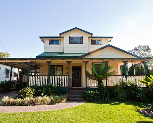 Beautiful two-story Sydney home with a spacious front porch and lush garden.