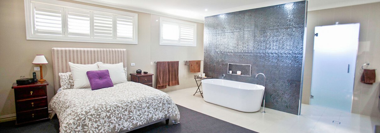 Interior of a contemporary bedroom featuring a freestanding bathtub, black accent wall, and ample na.