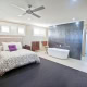Interior of a contemporary bedroom featuring a freestanding bathtub, black accent wall, and ample na.